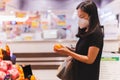 Woman in protective mask holding orange fruit supermarket.