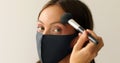 Woman in protective mask is making up