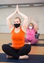 Woman in protective mask making yoga meditation in yoga pose - agni stambhasana