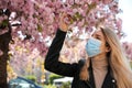 Woman with protective mask near blossoming tree. Seasonal pollen allergy Royalty Free Stock Photo