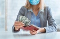 Woman in protective mask puts dollars in wallet Royalty Free Stock Photo