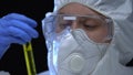 Woman in protective mask and respirator demonstrating inflammable liquid in tube