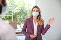 Woman in protective mask saying hello in office. Keeping social distance during coronavirus pandemic