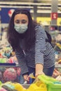 Woman in a protective mask in a supermarket chooses children`s toys. toned. vertical photo. toned