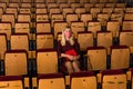 Woman in protective mask watching performance in empty theater hall