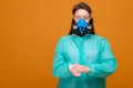 woman in protective medical equipment with antiseptic in hands medical mask on face on a yellow background, coronavirus pandemic