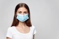 Woman protective medical mask on isolated background brunette in white t-shirt