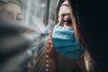 Woman in protective medical mask looking out of window