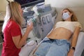 Woman in protective medical mask lying on couch in front of doctor with ultrasound diagnostics