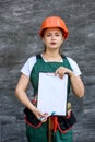 Woman in protective uniform and helmet posing with clipboard and tool belt Royalty Free Stock Photo