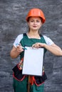 Woman in protective uniform and helmet posing with clipboard and tool belt Royalty Free Stock Photo