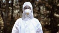 Woman in protective uniform and mask in forest exclusion zone, ecological crisis Royalty Free Stock Photo