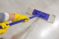 Girl in protective gloves cleaning floor using flat wet mop Royalty Free Stock Photo