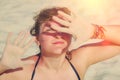 A woman protects her hands from the sun on the beach