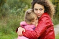 Woman protects little girl from wind in garden Royalty Free Stock Photo