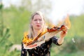 A woman protests against fake media news. Portrait of a young woman looking at a burning newspaper. A burning newspaper in a woman