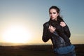 Woman pulling her scarf and posing in the dusk