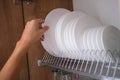 Woman pulling out white plate from shelf in kitchen closeup