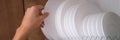 Woman pulling out white plate from shelf in kitchen closeup