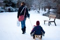 Woman pulling a sled with two kids on it