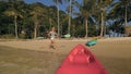 Woman pulls canoe with paddle to azure sea water from beach