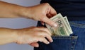 The woman pulls money out of the back pocket of the standing man's blue jeans. Close-up view of the hands. Place for text Royalty Free Stock Photo