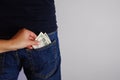 The woman pulls money out of the back pocket of the standing man's blue jeans. Close-up view of the hands. Place for text Royalty Free Stock Photo