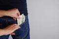 The woman pulls money out of the back pocket of standing man's blue jeans. Close-up view of the hands. Place for your text Royalty Free Stock Photo