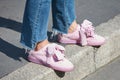 Woman with Puma suede pink shoes and torn blue jeans trousers before Trussardi fashion show, Milan Fashion