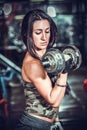 Woman pumping up muscules with dumbbells