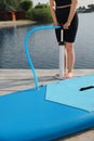 Woman pumping up SUP board on pier, closeup Royalty Free Stock Photo