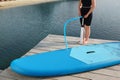 Woman pumping up SUP board on pier, closeup Royalty Free Stock Photo