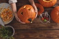 Woman with pumpkin jack o`lantern at wooden table, top view. Halloween celebration