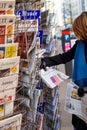 Woman purchases a Le Monde French Press newspaper from a newsstand