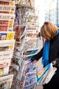 Woman purchases a Un Doigt French newspaper from a newsstand