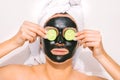 Woman with purifying charcoal facial mask holding cucumber slices on her eyes Royalty Free Stock Photo