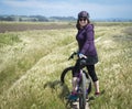 Woman in purple shirt standing with mountain bike
