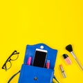 Woman purse, beauty products, smartphone, glasses on a bright yellow background, top view Royalty Free Stock Photo