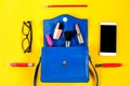 Woman purse, beauty products, smartphone, glasses on a bright yellow background, top view