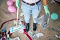 Woman with pushbroom cleaning mess of floor in room after party confetti