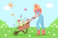 Woman pushing garden cart with flowers on the meadow. Sunny landscape