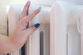 Woman put her hands on metallic radiator, white battery. Concept of heating systems, heat season Royalty Free Stock Photo