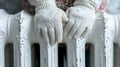 a woman put her hands in white knitted gloves on a white cast iron radiator, cold no heat, warm radiator.