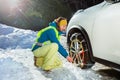 Woman put winter chains on car wheel for icy road Royalty Free Stock Photo
