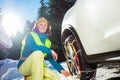 Woman put on winter chains for car wheel at snowy road Royalty Free Stock Photo