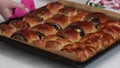 The woman puts a baking sheet with baked buns on the stand. Bunks with different fillings. Close-up