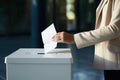 A woman puts a bill into the ballot box at the polling station