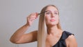 Woman puts black mascara on her eyelashes with makeup, photo of attractive blonde on a white and gray background. Royalty Free Stock Photo