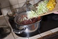 a woman puts cabbage in a saucepan,ingredients for cooking borsch soup