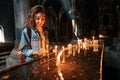 Woman puts a candle and prays in a church or Catholic church. The concept of sorrow and hope in faith Royalty Free Stock Photo